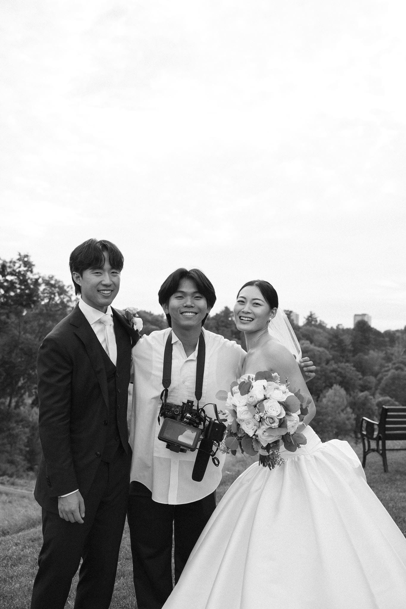 Danny, in the middle with his camera rig around his neck, smiling, with Helen on one side and Jason on the other. A black and white photograph.